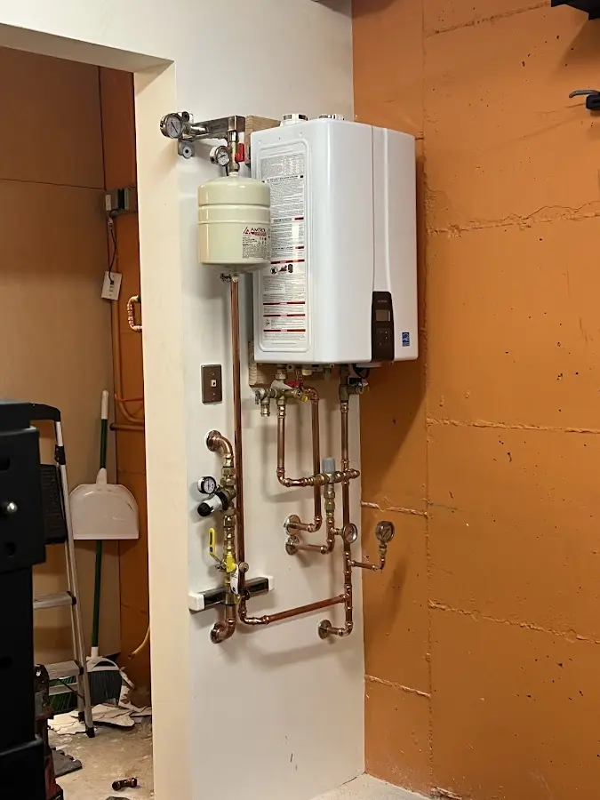 Plumbing technician inspecting water heater connections in Freeland